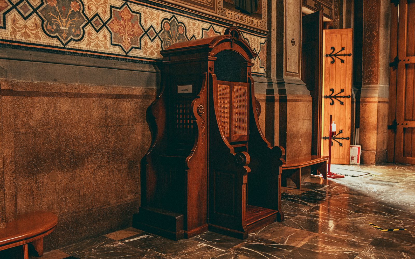 Confesionario de madera con su celosía en una iglesia