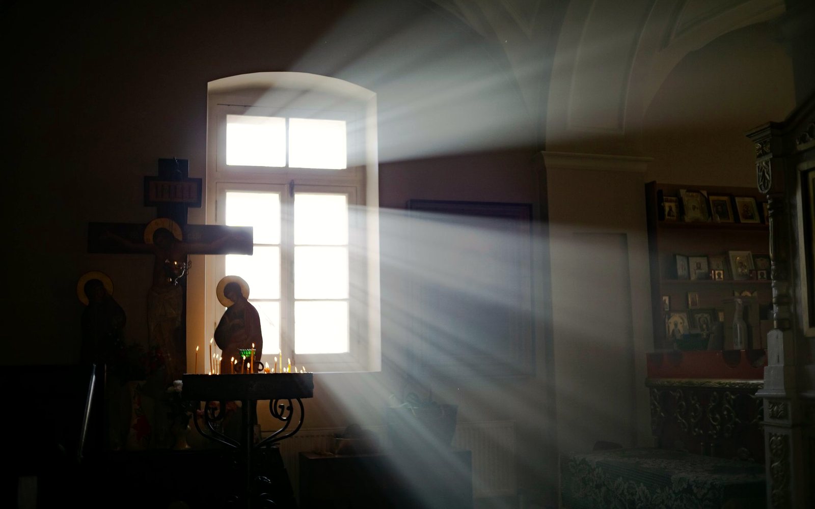 Crucifijo e iconos junto a una ventana con rayos de luz en una iglesia