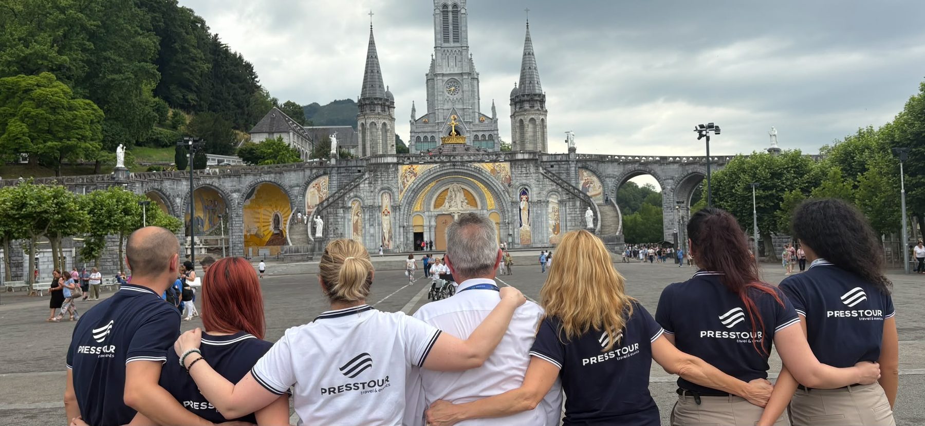 El equipo de Presstour, de espaldas y abrazado, ante la basílica del Santuario de Lourdes